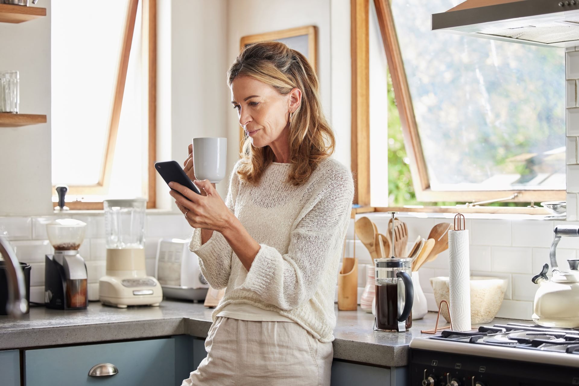 a woman drinking a coffee while looking at her phone