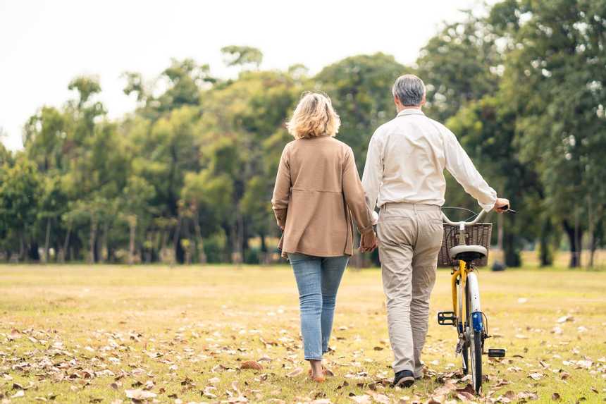 a couple walking through a park and pushing a bike