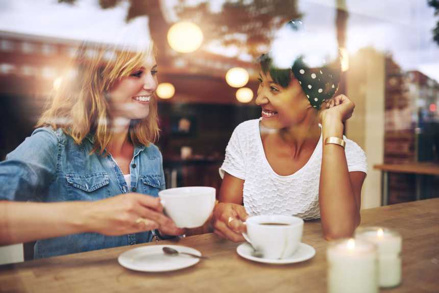 two women talking while drinking coffee