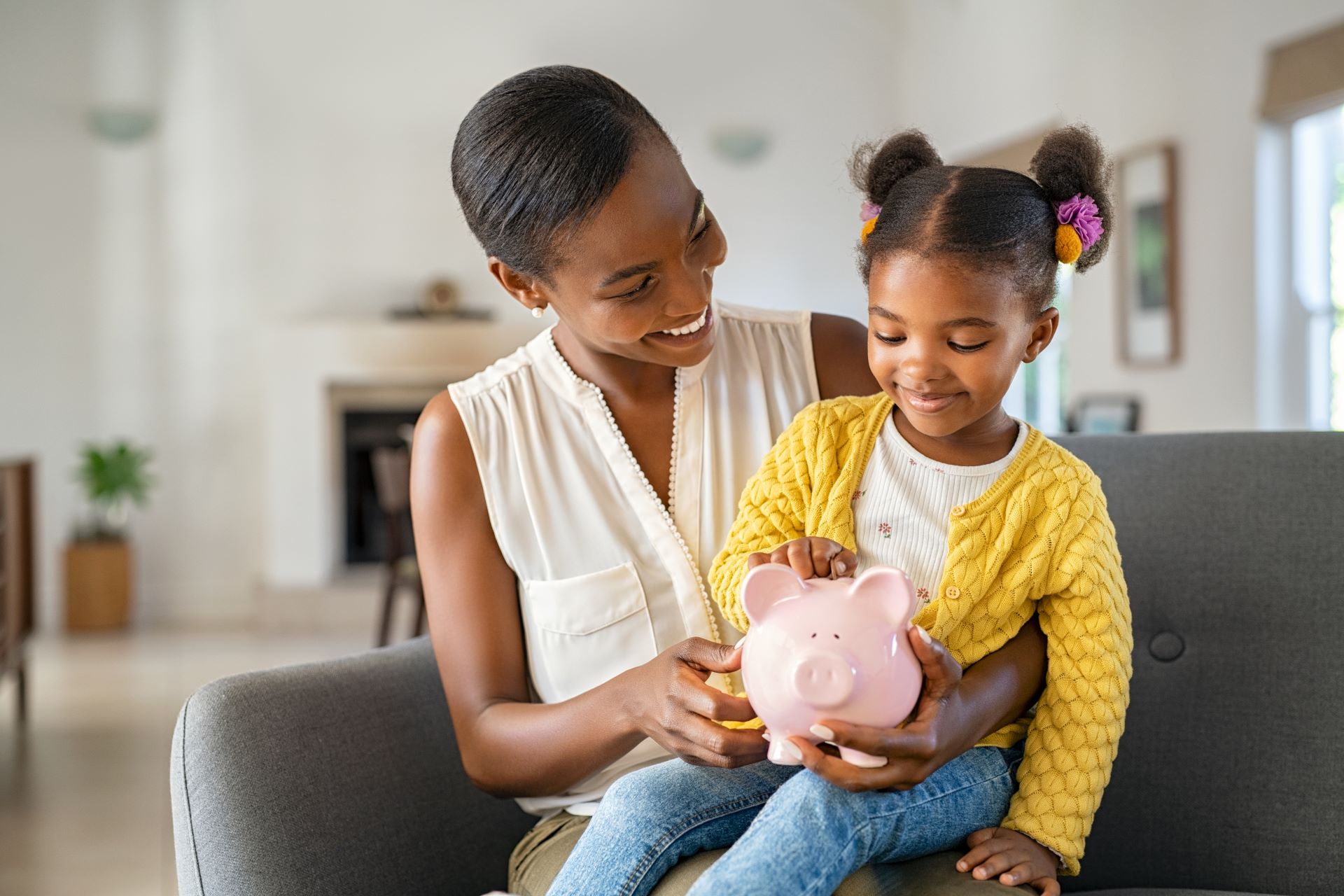 a woman with a child on her knee with a piggy bank