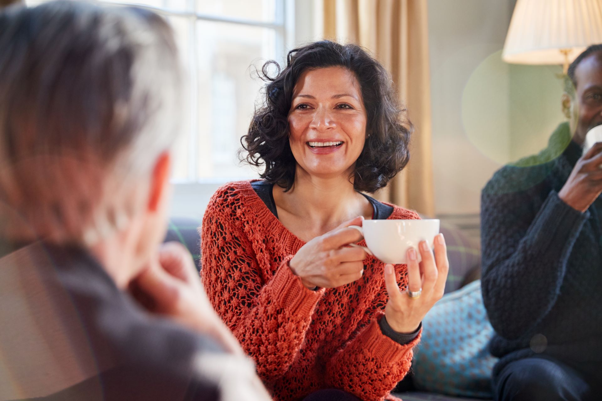 a woman talking to a man while drinking tea